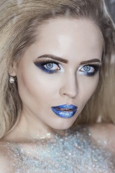 Winter Beauty Woman. Christmas Girl Makeup. Holiday Make-up. Snow Queen High Fashion Portrait over Blue Snow Background.