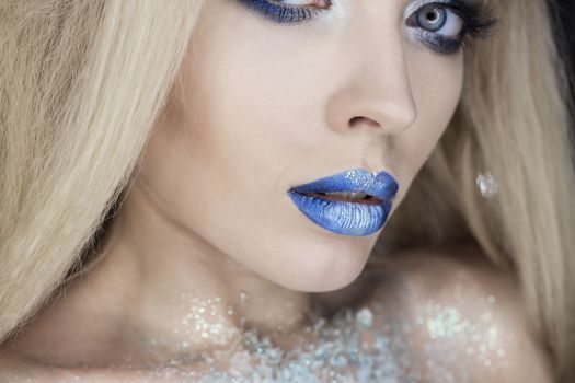Winter Beauty Woman. Christmas Girl Makeup. Holiday Make-up. Snow Queen High Fashion Portrait over Blue Snow Background.
