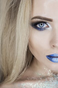 Winter Beauty Woman. Christmas Girl Makeup. Holiday Make-up. Snow Queen High Fashion Portrait over Blue Snow Background.