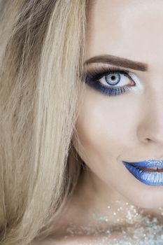 Winter Beauty Woman. Christmas Girl Makeup. Holiday Make-up. Snow Queen High Fashion Portrait over Blue Snow Background.