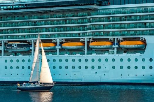 Blue sailboat traveling against the cruise liner in Riga