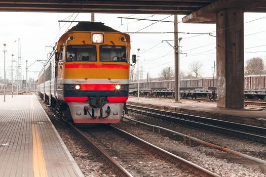 Old yellow passenger diesel train moving at the terminal