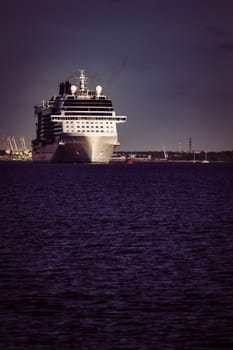 Giant white passenger ship moving past the port on a clear day