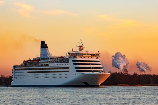 White passenger ship moving against the orange sunset sky