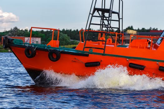 Orange pilot boat moving by the river in Europe. Rescue service