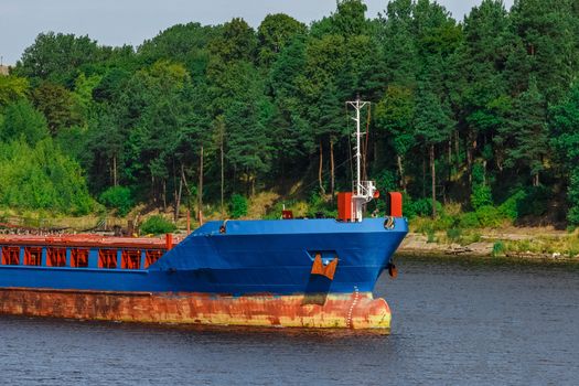 Blue cargo ship with long reach excavator moving to the port