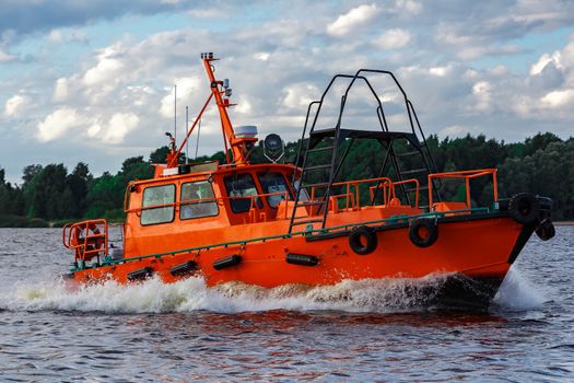 Orange pilot boat moving by the river in Europe. Rescue service