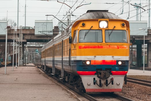 Old yellow passenger diesel train moving at the terminal