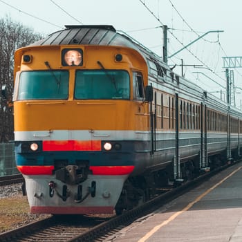 Old yellow passenger diesel train moving at the terminal