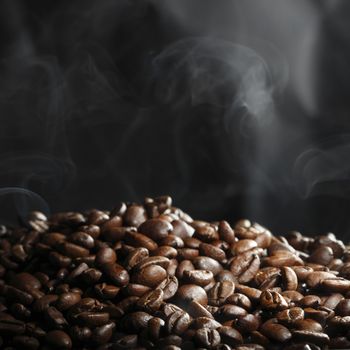 Hot roasted coffee beans and steam on black