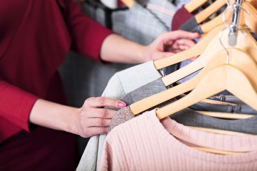 Closeup shot of hands of woman who choosing new clothes, fashion shop concept