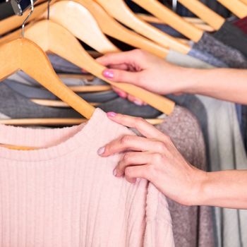 Closeup shot of hands of woman who choosing new clothes, fashion shop concept