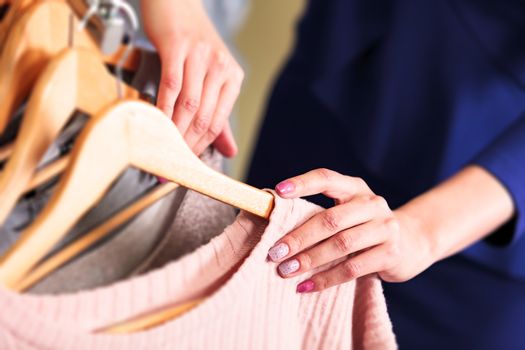 Closeup shot of hands of woman who choosing new clothes, fashion shop concept