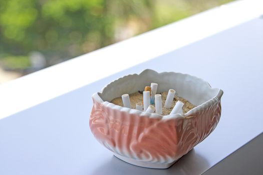 The pink ashtray is placed on the table.
