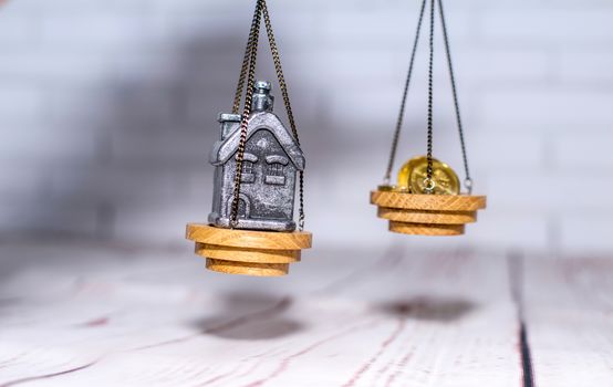 Stack of coins and a small house on the scales. The concept of choice, cash savings and purchase of real estate