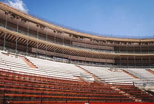 view from below of a stadium with covered tribunes and wooden seats