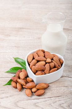 Almond milk in bottle with almond on wooden background.