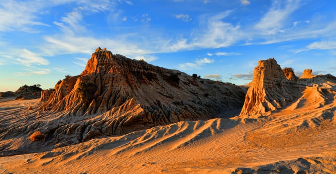 Rock landforms in the outback desert with wspy high cloud overhead,