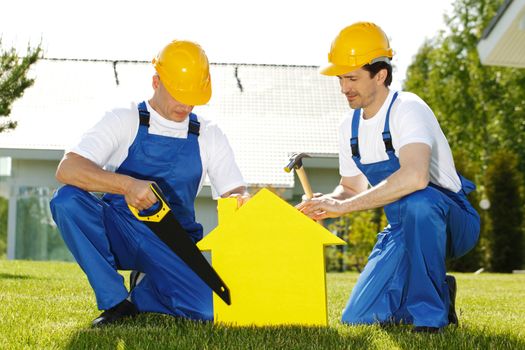 Workers with tools and house symbol. Construction concept