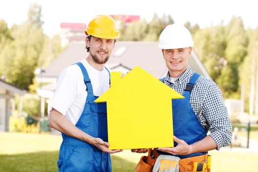 Construction workers showing house model symbol and friendly smiling