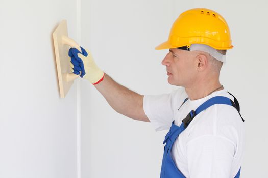 Builder working with grinding tool aligning wall indoors