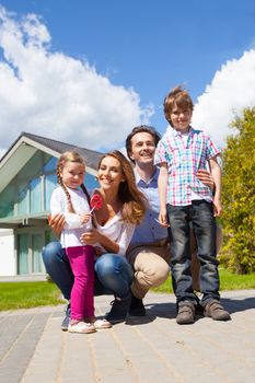 Portrait of happy smiling family and their children near their house