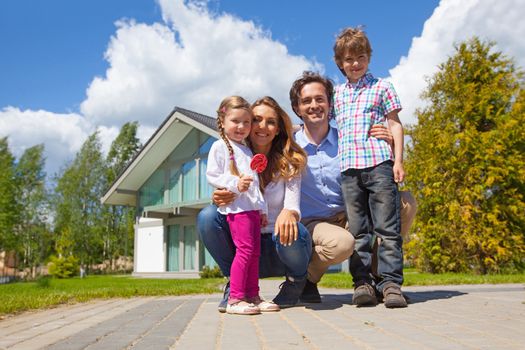 Portrait of happy smiling family and their children near their house
