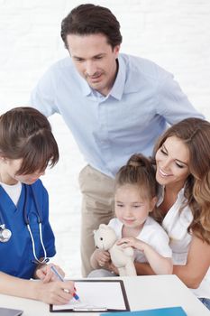 Young pediatrician doctor talking with girl and her parents