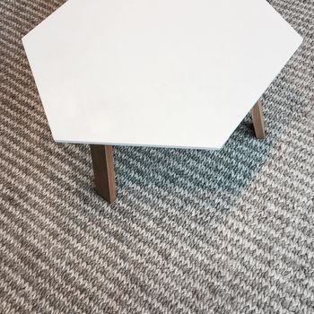 Modern white table on gray knitted rug. Scandinavian design.