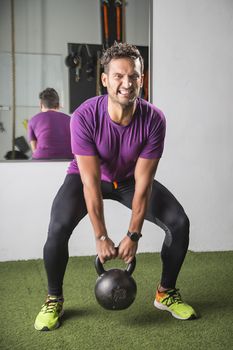 man in his thirties, pulling on a heavy cast iron kettlebell