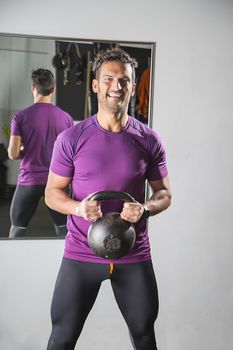 man in his thirties, pulling on a heavy cast iron kettlebell