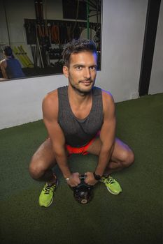 young man in squat position holding a kettlebell
