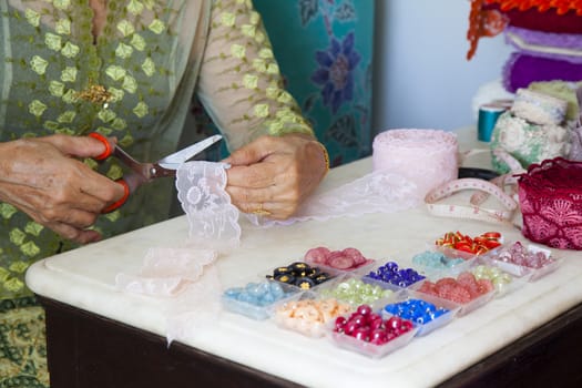 Tailor Woman, fashion designer working at studio. Fashion designer cutting textile next to a sewing machine. Fashion Designer Cutting Fabric In Studio