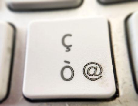 close-up view of of the button of a computer keyboard with the letter "ò" and the "@" symbol