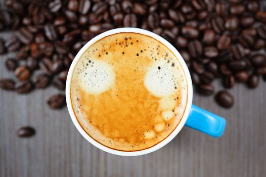 small blue cup of fresh espresso with crema on table, view from above