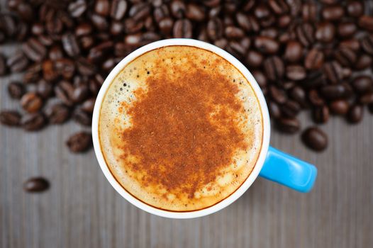 small blue cup of fresh espresso with cinnamon on table, view from above