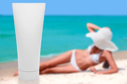 Tube of sun lotion with slim tanned woman on a beach behind. Summer holidays