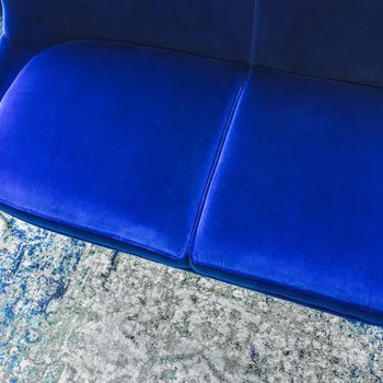 Close-up of a luxurious blue velvet sofa on a fashionable rug. Classy furniture.