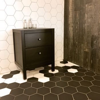 Spacious bathroom with tiled floor and wall, and black drawer unit. Contemporary design.