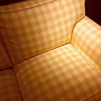 Checked armchair in spotlight. Classic style comfortable furniture.