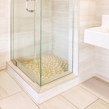 Modern renovated shower with tiled walls and floor, in beige tones.