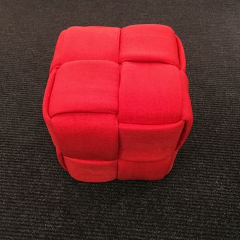 Red cube chair on gray carpet floor. Modern design furniture.