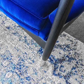 Close-up of a luxurious blue velvet armchair on a fashionable rug. Classic style furniture.