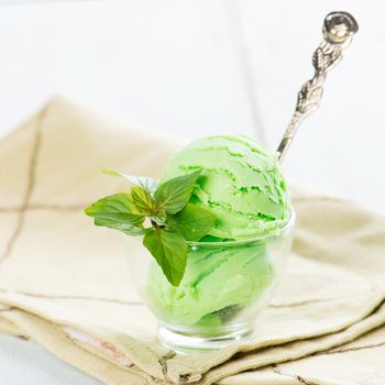 Cup of mint ice cream on wooden background.