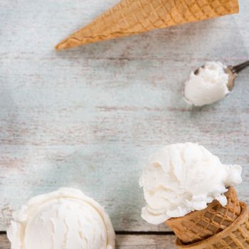 Top view white ice cream wafer cone on bright rustic wooden background. Copy space in middle.