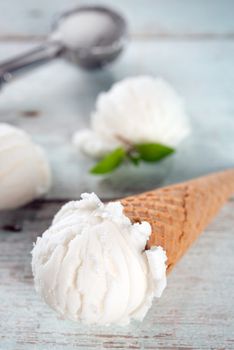 Vanilla ice cream wafer cone on white rustic wooden background. 