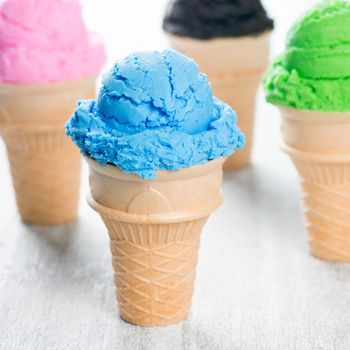 Chocolate, matcha, blueberry and strawberry ice cream in the cone on wooden background.