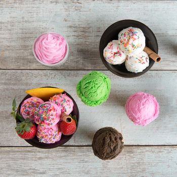 Top view various flavor ice cream in bowl on white rustic wooden background.