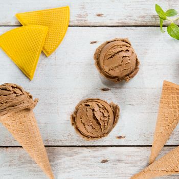 Top view cocoa ice cream in waffle cone on old rustic vintage wooden background.