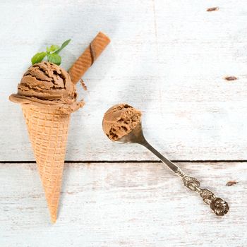 Top view chocolate ice cream in waffle cone on old rustic vintage wooden background.